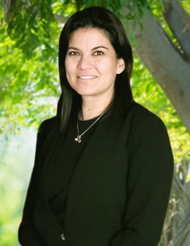 Alicia in the nature with a black suit smiling