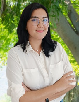 Estefania in the nature wearing a white t-shirt and smiling at the camera