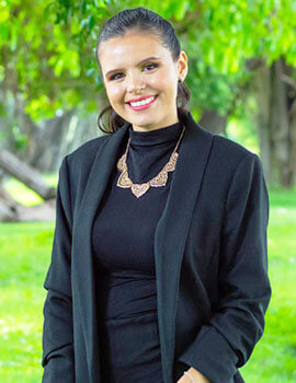 Katherine standing up in the nature with black clothes smiling at the camera